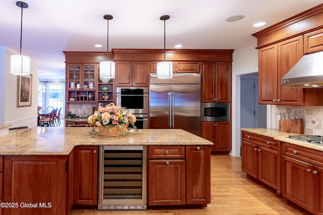 kitchen with wine cooler, light wood finished floors, a kitchen island, built in appliances, and under cabinet range hood