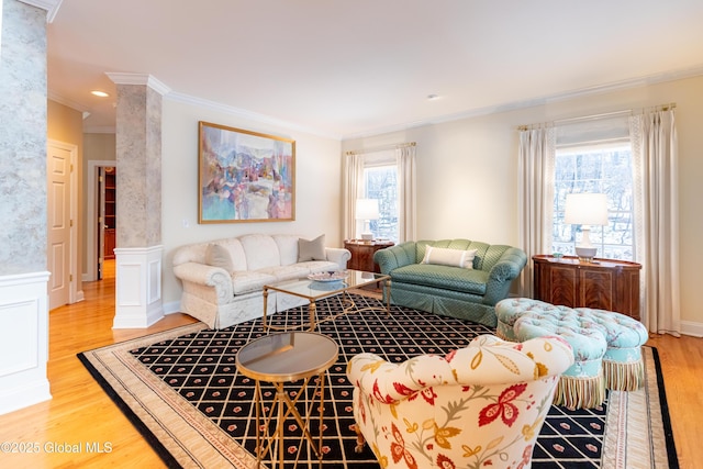 living area featuring ornamental molding, wainscoting, decorative columns, and light wood finished floors