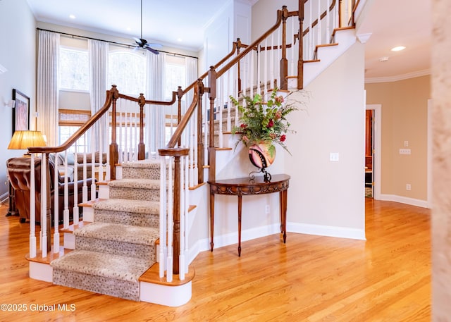 stairs featuring ceiling fan, crown molding, baseboards, and wood finished floors