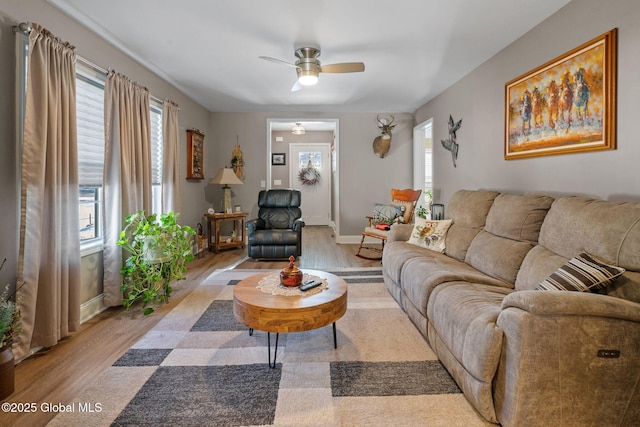 living area featuring a ceiling fan, light wood-style flooring, and baseboards