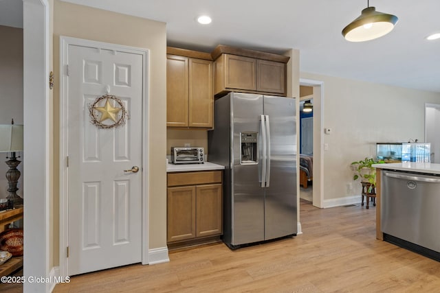 kitchen featuring appliances with stainless steel finishes, decorative light fixtures, light countertops, light wood-style floors, and recessed lighting