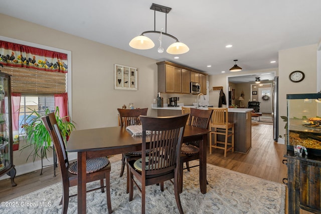 dining area featuring baseboards, light wood finished floors, a ceiling fan, and recessed lighting