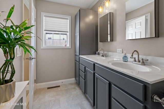 bathroom with double vanity, baseboards, visible vents, and a sink