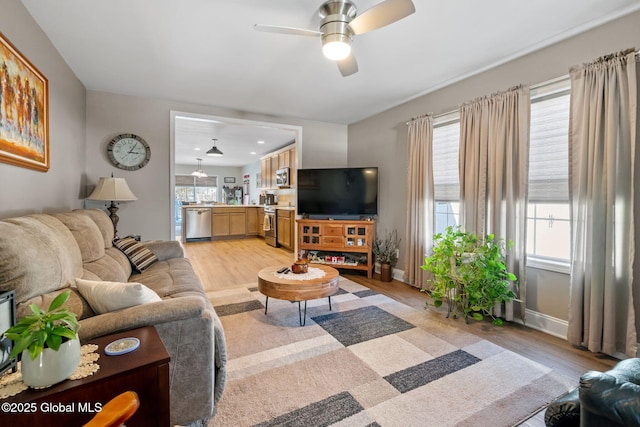 living room with light wood-type flooring, ceiling fan, and baseboards