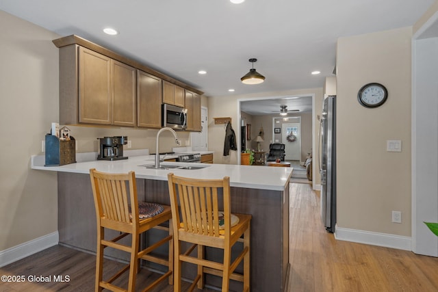 kitchen with appliances with stainless steel finishes, light countertops, a sink, and a peninsula