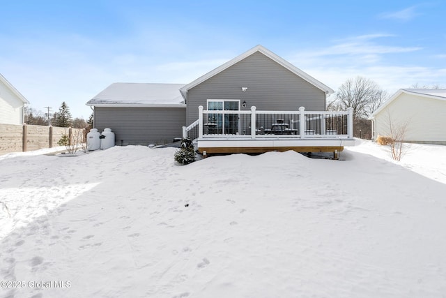 snow covered house with a deck and fence