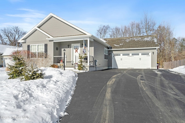 view of front facade with aphalt driveway, covered porch, an attached garage, and board and batten siding