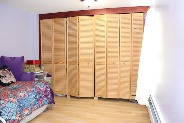 bedroom with light wood finished floors and baseboard heating