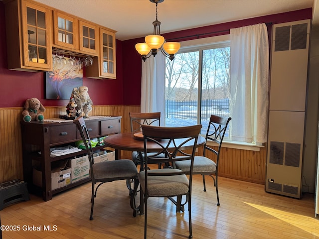 dining space with a wainscoted wall, a heating unit, light wood-style flooring, and wooden walls