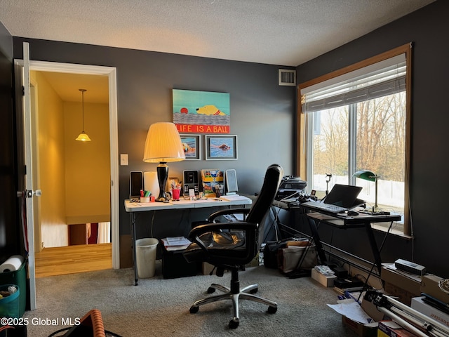 carpeted office space featuring visible vents and a textured ceiling