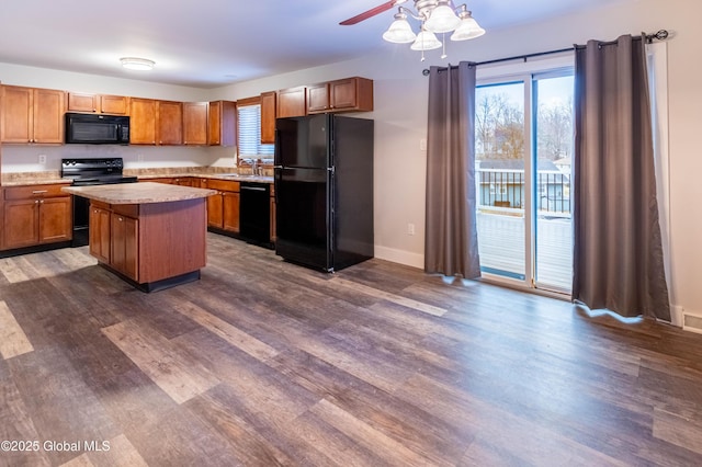 kitchen with a kitchen island, dark wood finished floors, light countertops, black appliances, and a sink