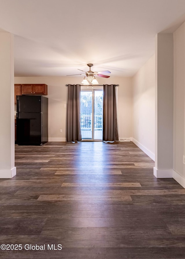 unfurnished living room with dark wood finished floors, a ceiling fan, and baseboards