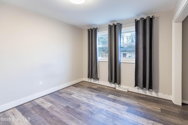 unfurnished room with visible vents, baseboards, and wood finished floors