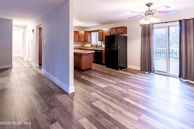 kitchen featuring baseboards, dark wood finished floors, light countertops, black appliances, and a sink