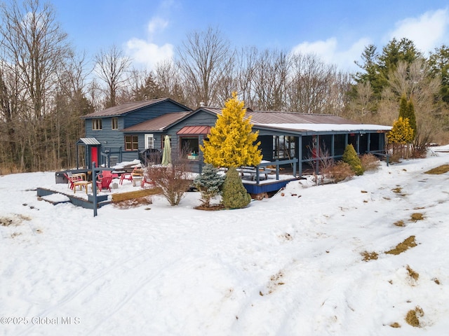 snow covered rear of property featuring metal roof and a standing seam roof