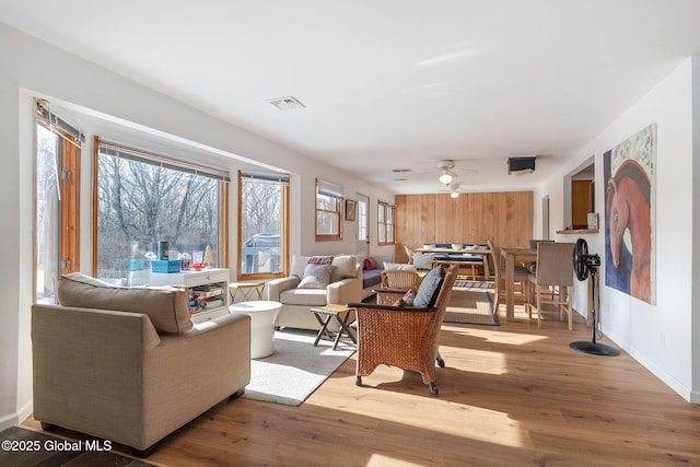 living room with visible vents, ceiling fan, baseboards, and wood finished floors