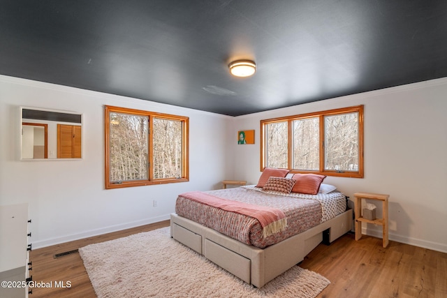 bedroom featuring wood finished floors, visible vents, and baseboards