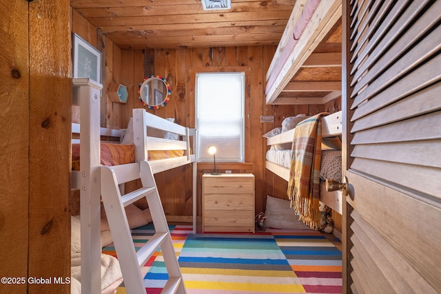 bedroom with wood ceiling and wood walls