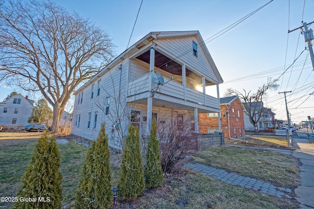 view of front of property featuring a front lawn, a balcony, and fence