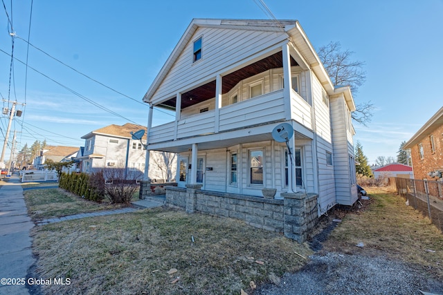 view of front facade featuring a porch, a balcony, and fence