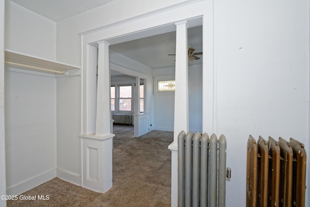 corridor with carpet flooring, radiator heating unit, and baseboards