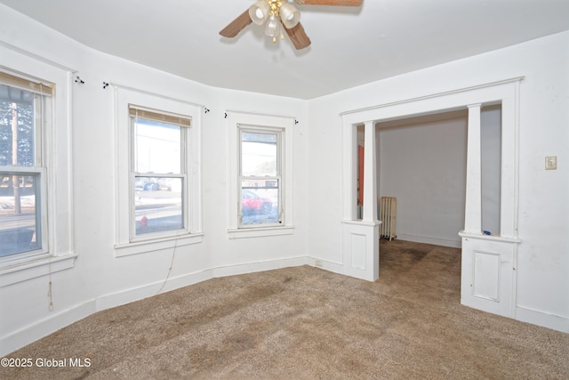 carpeted empty room with baseboards, radiator, and a ceiling fan