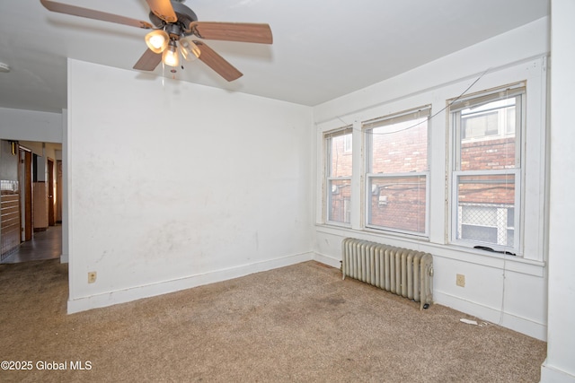 spare room with radiator, a ceiling fan, baseboards, and carpet floors