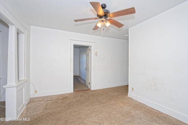 carpeted spare room featuring baseboards and ceiling fan