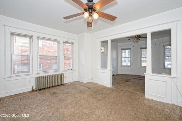 unfurnished room with radiator, baseboards, ornate columns, carpet floors, and ceiling fan