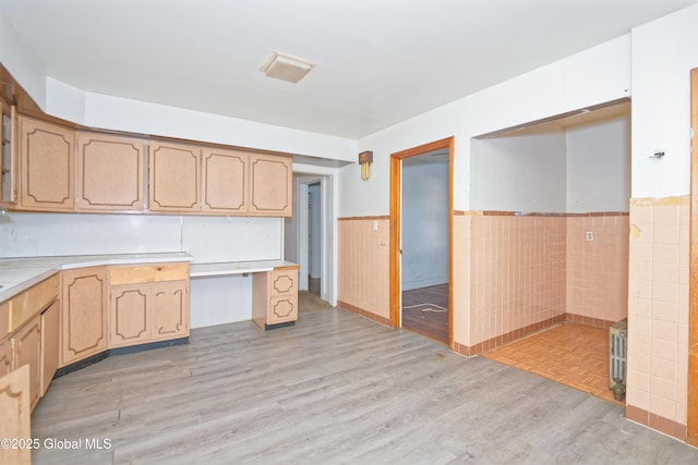 kitchen with wainscoting, tile walls, light countertops, and light wood-style floors