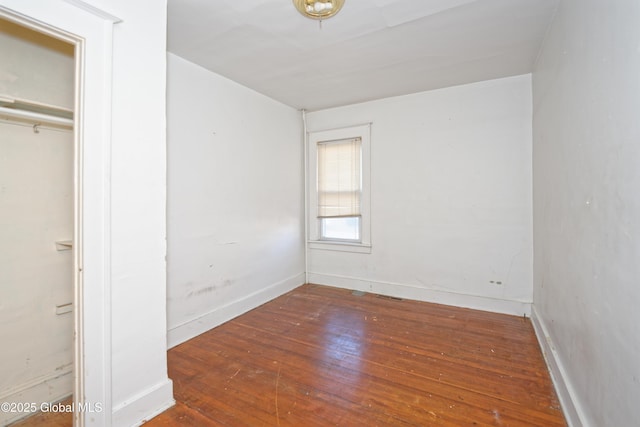 unfurnished bedroom featuring hardwood / wood-style floors, baseboards, and a closet