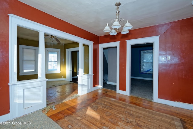 unfurnished room with baseboards, wood-type flooring, and ceiling fan with notable chandelier