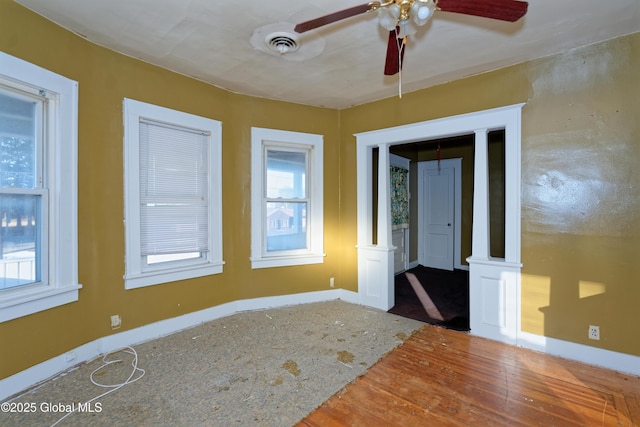 empty room with visible vents, wood finished floors, and a ceiling fan