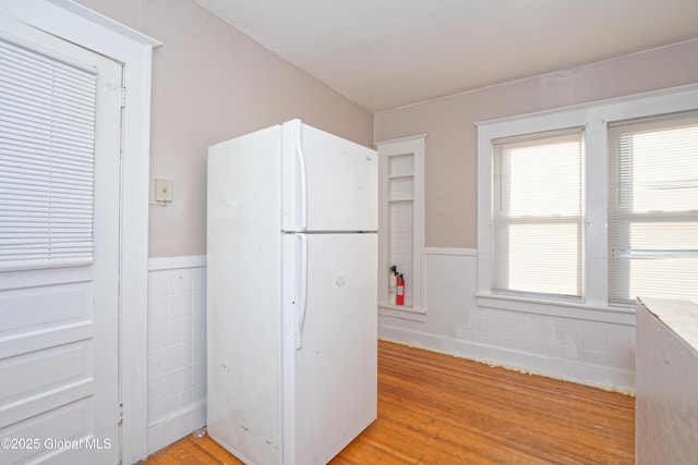 kitchen with tile walls, wainscoting, and freestanding refrigerator