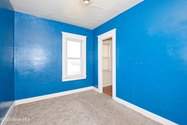 spare room with baseboards and carpet