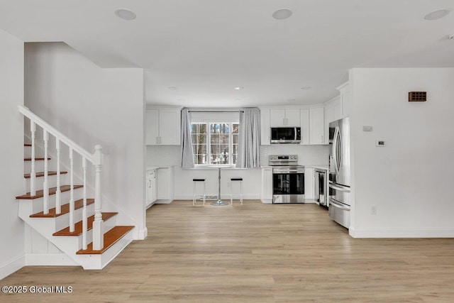 living room with light wood-style floors, stairway, and baseboards