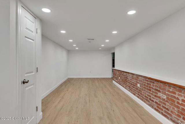 spare room featuring recessed lighting, brick wall, visible vents, baseboards, and light wood-type flooring