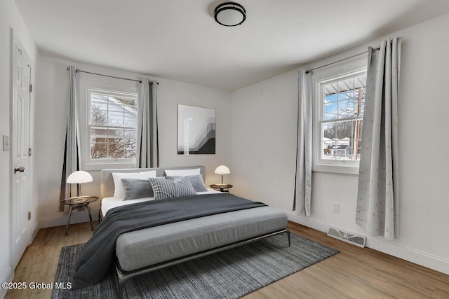 bedroom featuring visible vents, baseboards, and wood finished floors