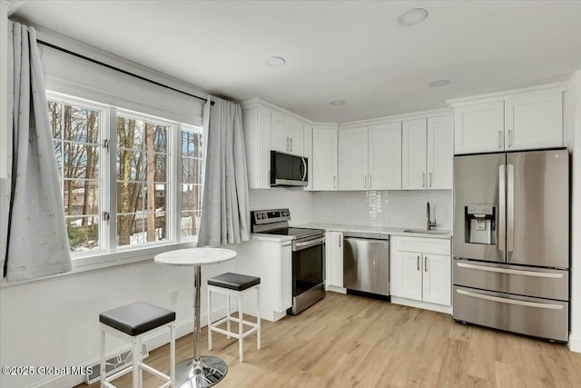 kitchen featuring appliances with stainless steel finishes, light countertops, a sink, and white cabinetry