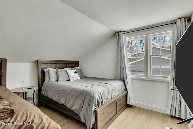 bedroom with vaulted ceiling, baseboards, and wood finished floors