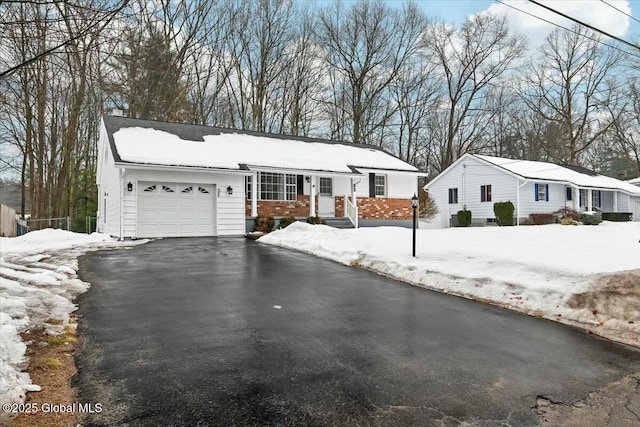 view of front facade featuring aphalt driveway, brick siding, and an attached garage