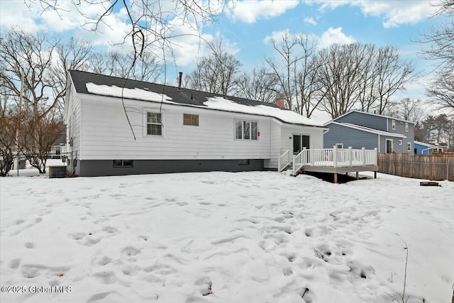 snow covered rear of property featuring fence, a chimney, and a wooden deck