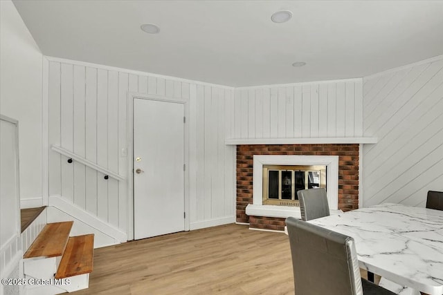 dining space with light wood finished floors, a fireplace, and stairway