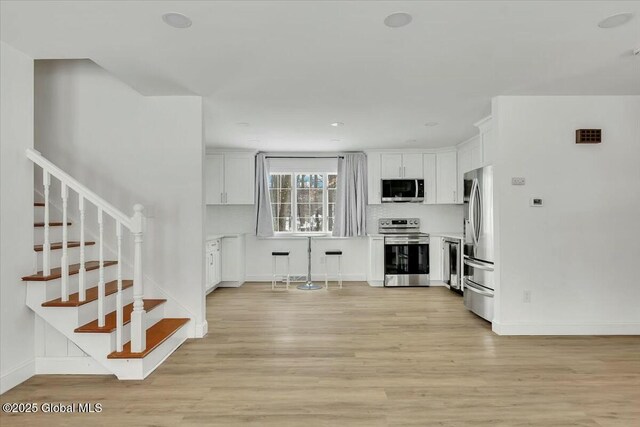 living room featuring light wood-type flooring, stairs, and baseboards