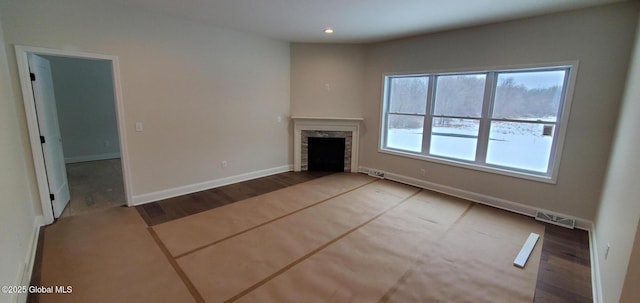 unfurnished living room with a fireplace, recessed lighting, visible vents, wood finished floors, and baseboards