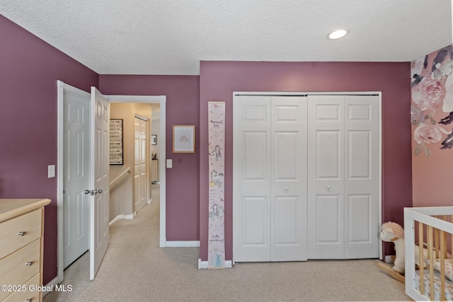 bedroom with a textured ceiling, a closet, and light colored carpet