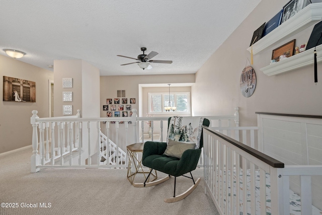 living area with carpet, a textured ceiling, and an upstairs landing