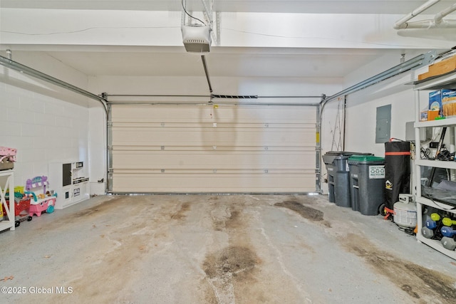 garage featuring concrete block wall, electric panel, and a garage door opener