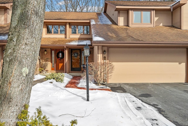 townhome / multi-family property featuring aphalt driveway, a shingled roof, and a garage