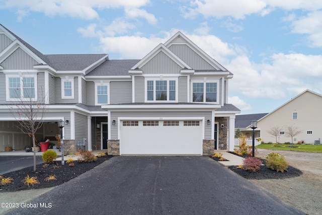 craftsman house featuring board and batten siding, stone siding, and driveway